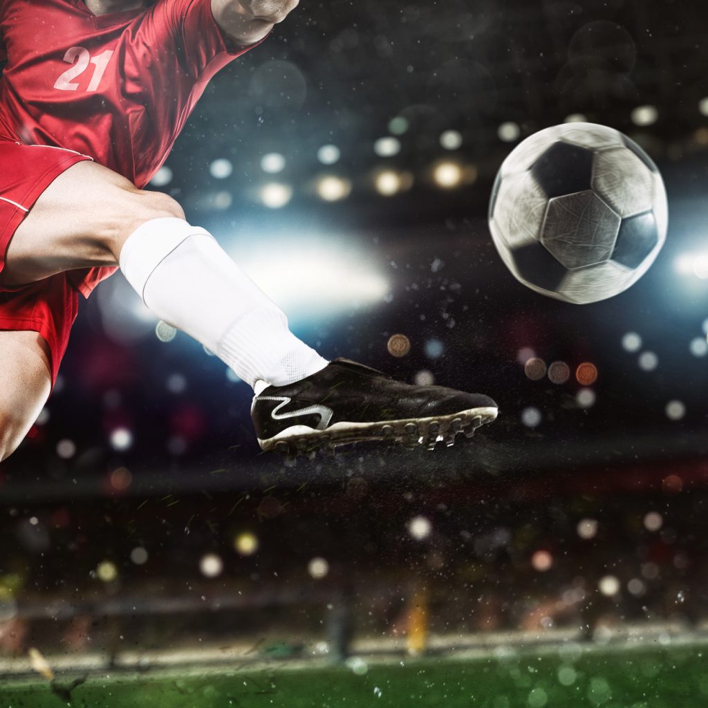 Soccer player kicks the ball vigorously at the stadium