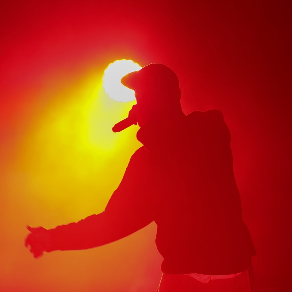 Unreconizable hip hop artist with mic in hand performing on concert stage